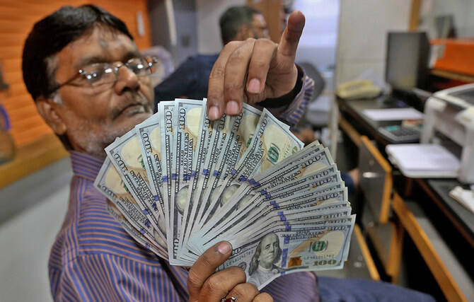 تاجر عملة باكستاني يفحص أوراق نقدية من فئة 100 دولار أمريكي في مكتب صرافة بكراتشي