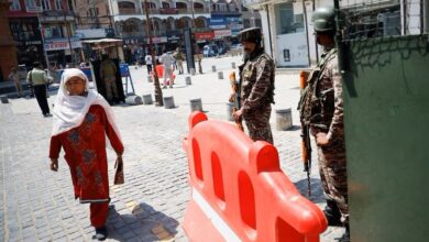 سيدة كشميرية تمر من أمام جنود حراسة في كشمير المحتلة